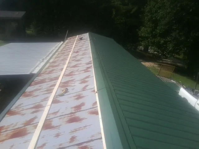 Old rusted panels beside newly installed green metal roofing — Wind Damage Roof Repair by Roofing Brothers in Lagrange