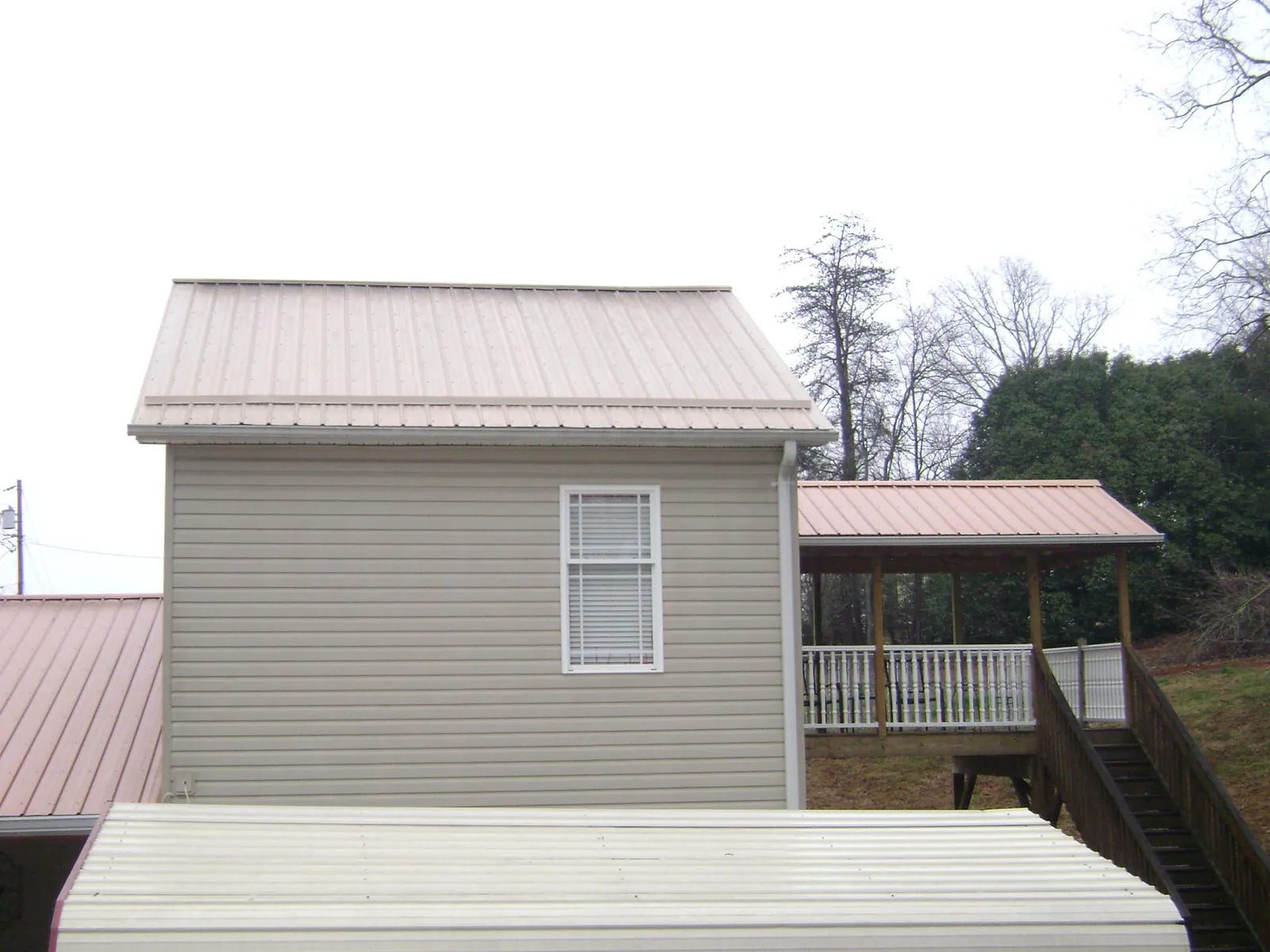 Tan metal roofs on a two story addition and attached porch, from a Roof Replacement job in Lagrange